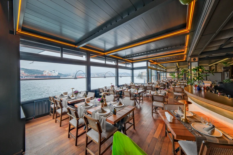Waterfront restaurant dining area beneath a closed bioclimatic pergola.