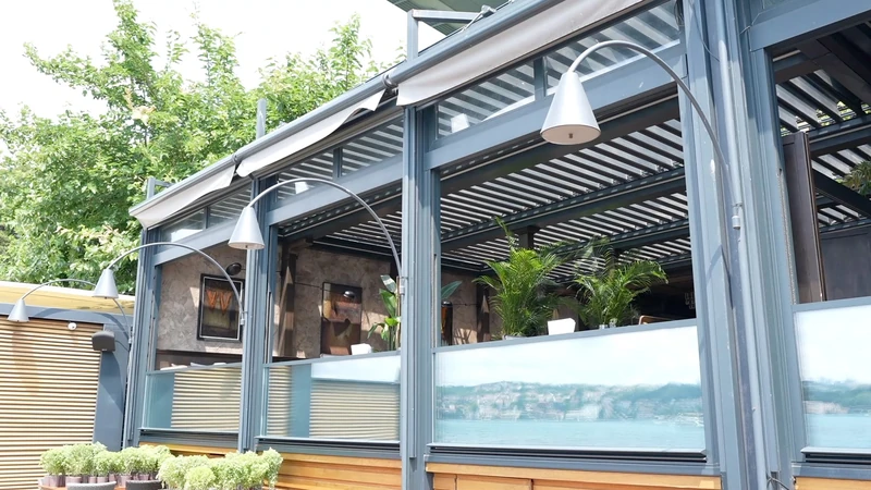 Upglass panels open beneath a pergola at a commercial waterfront terrace.
