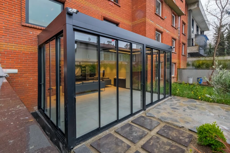 Sliding glass enclosure beside a residential brick exterior.