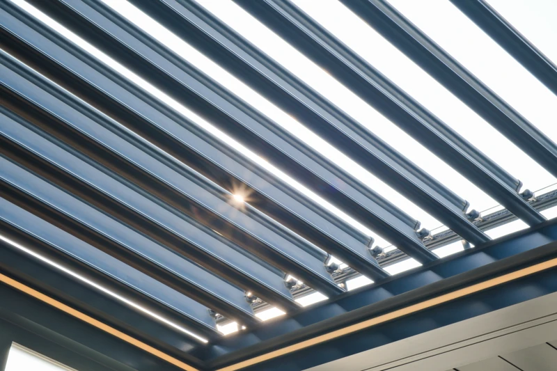 Sunlight filtering between tilted aluminum louvers.